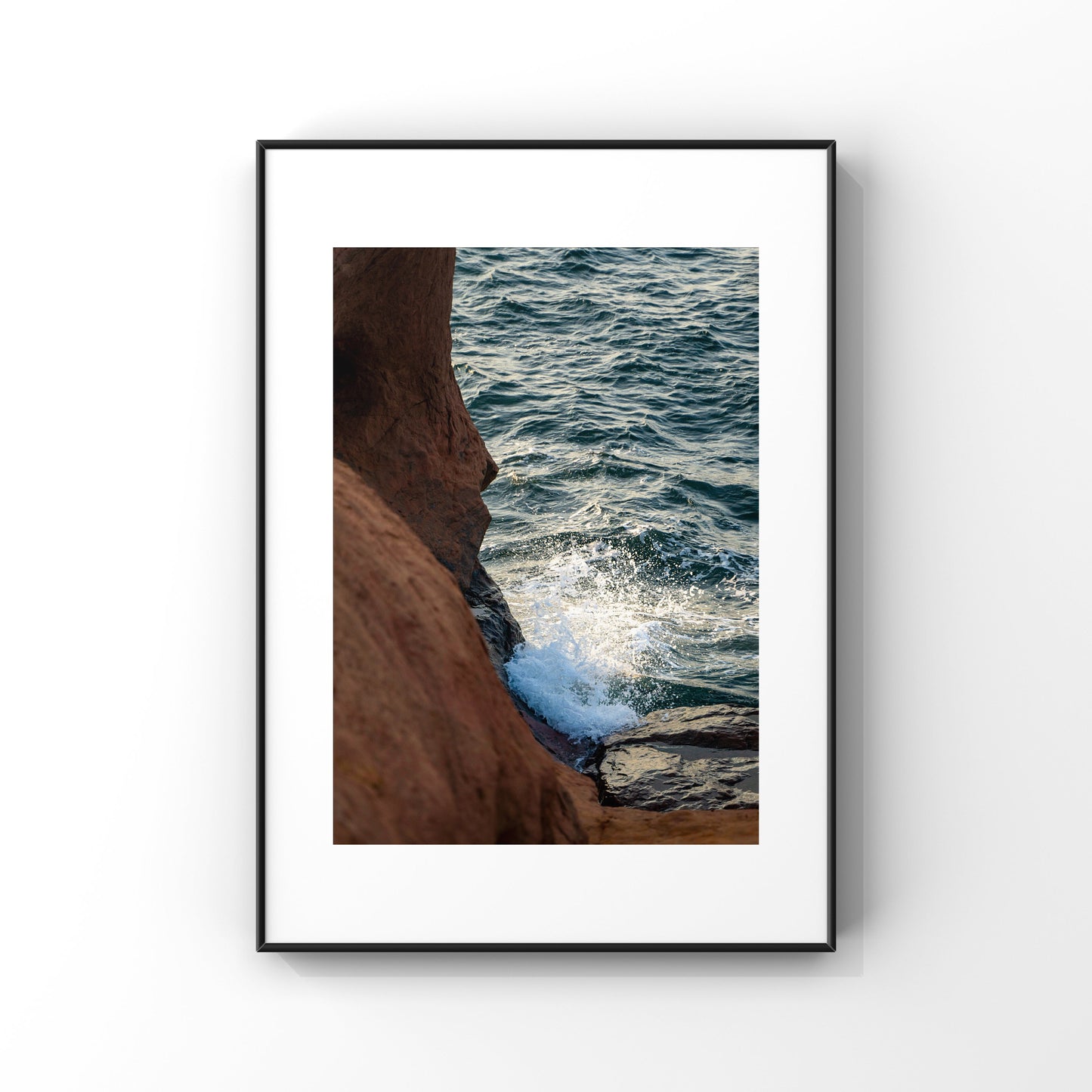 Photography print of a waves splashing on the rocky orange cliffs of Magdalen Islands in Quebec