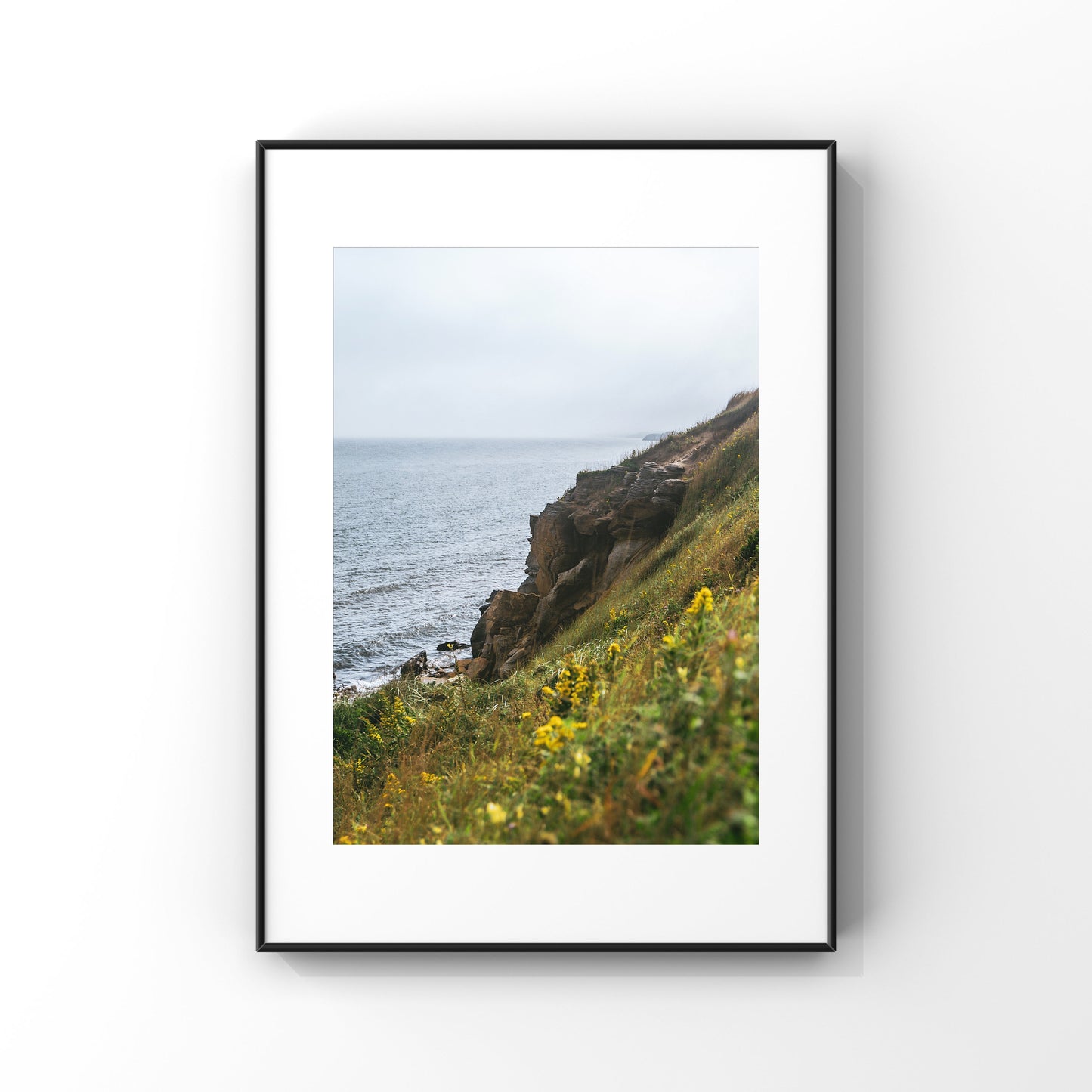 Luscious green and yellow vegetation embracing the rocky cliffs of Magdalen Islands in QUebec