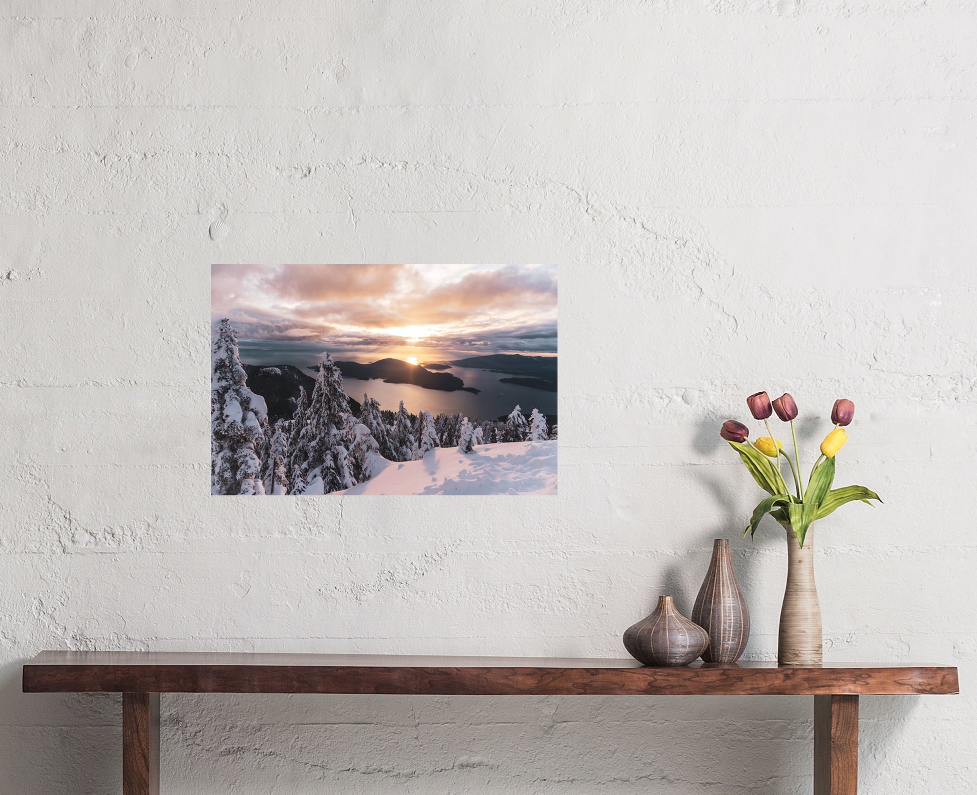 Mountain sunset photography print of the north shore mountains in Vancouver, British Columbia. The sky is peach, yellow and pink, the trees are covered in snow, there is a bird flying in the sky.